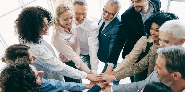 Group of diverse professionals joining hands in unity.