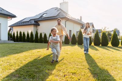 A family enjoys playing outside their home on a sunny day.