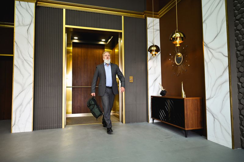 Confident mature entrepreneur leaving elevator in stylish office lobby