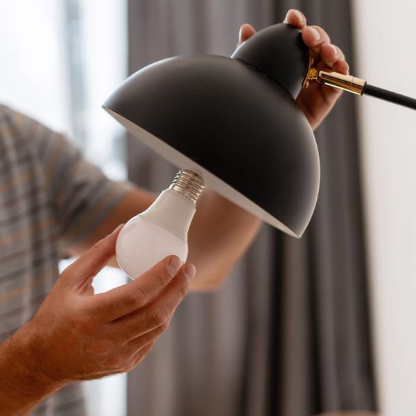 Person inserting a light bulb into a lamp.