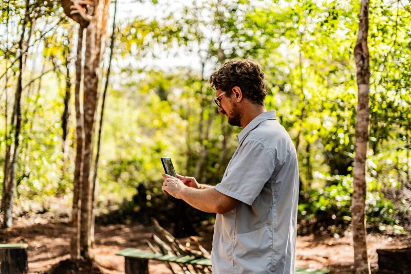 Tourist taking photos with smartphone during cultural visit to Curripaco indigenous tribe