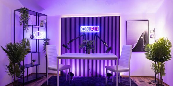 Modern podcast setup with "ON AIR" neon sign and purple lighting.