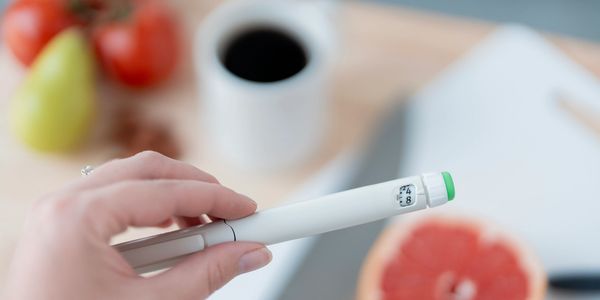 Hand holding a glucose meter showing a blood sugar level of 8.
