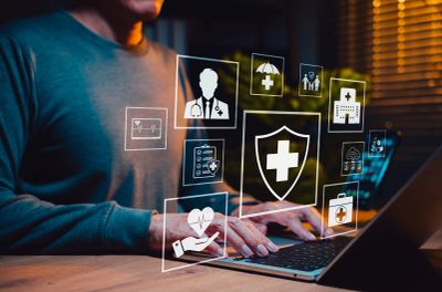 Person using laptop with healthcare icons floating.