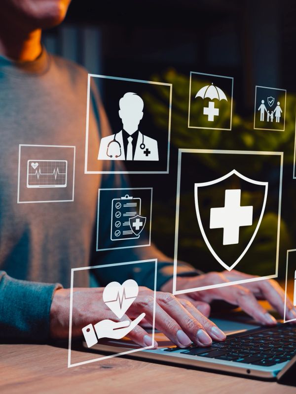 Person typing on laptop with medical icons overlay.