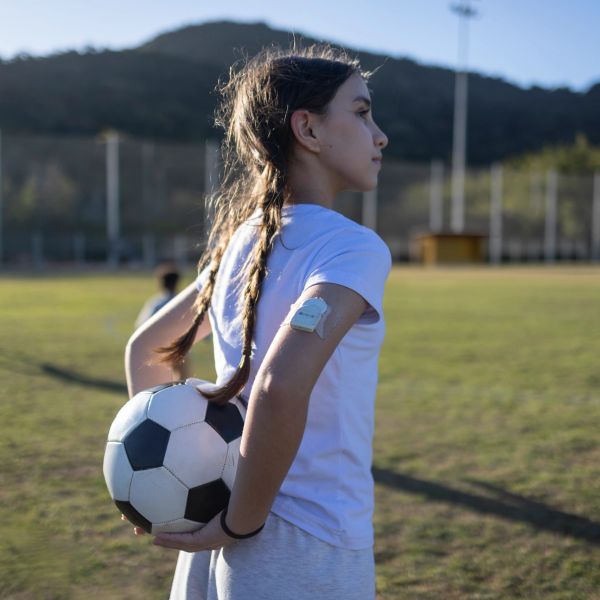 Young girl holding a soccer ball on a field, looking determined.