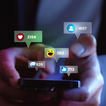 Person holding phone with social media reaction icons floating above.