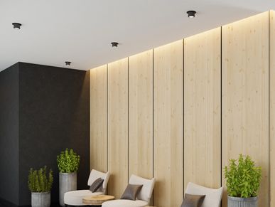 Modern lounge area with round chairs, wooden tables, and tall planters against a light wood-paneled wall.