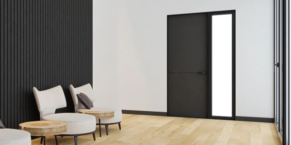 Modern minimalist room with black accent wall, light wood floor, and simple seating.