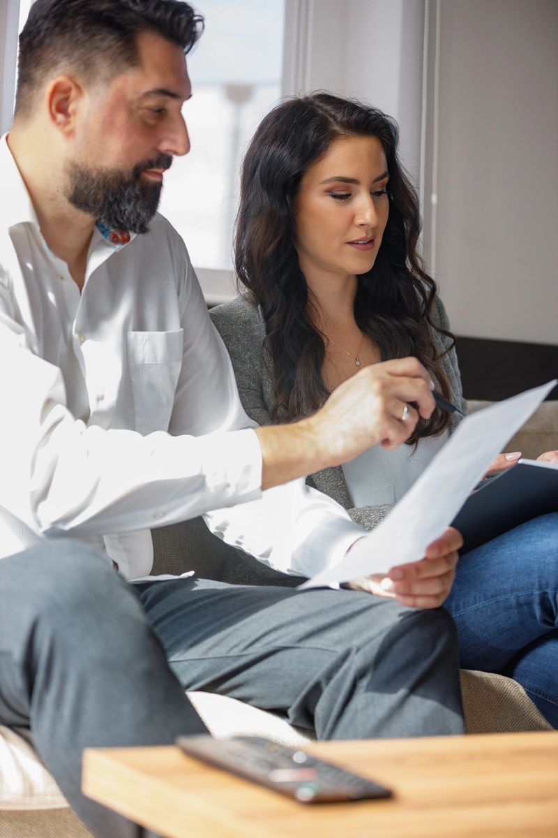 Beautiful businesswoman financial advisor sitting in the lounge next to her male colleague, reading documents and creating investment project together
