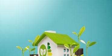 A small eco-friendly house model with green roof and energy efficiency icons.