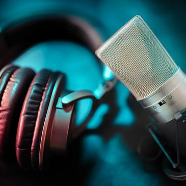 Close-up of headphones and a microphone in a studio setting.