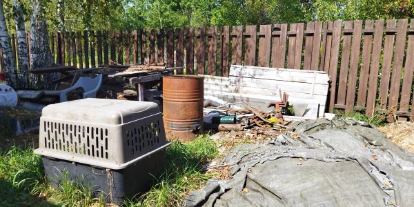 Outdoor area with old objects and brown wooden fence.