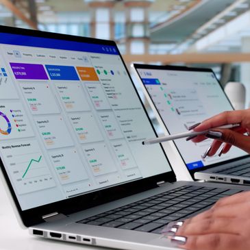 Person analyzing data on laptop screens in an office.