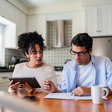 Couple reviewing finances at home with tablet and documents.