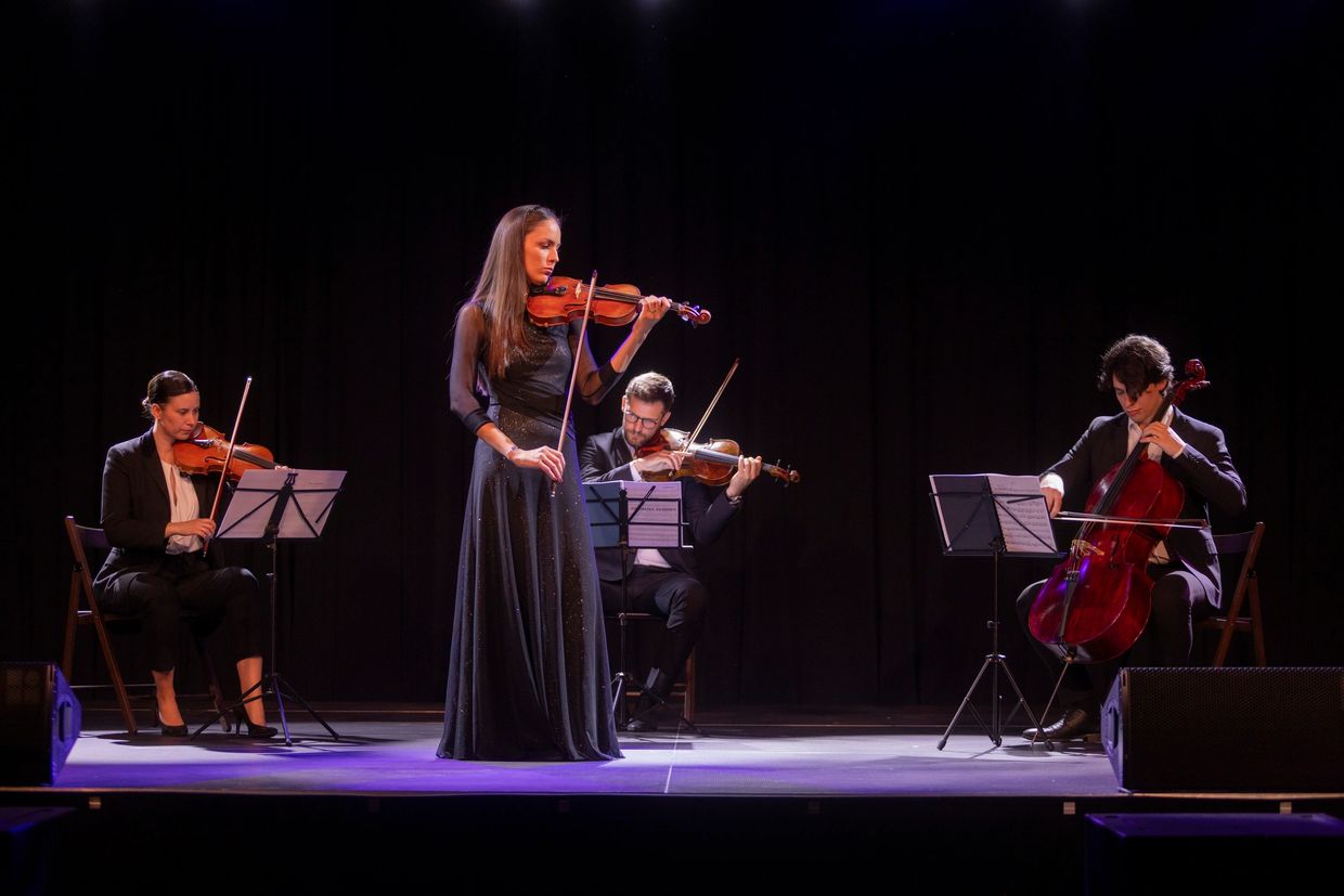 A string quartet performing on stage with focused expressions.