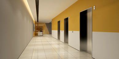 Modern elevator lobby with yellow and white walls and shiny tiled floor.