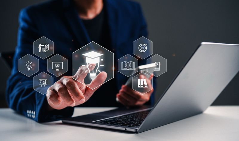 A person interacts with digital icons representing education and technology on a laptop, showcasing a modern approach to learning and information access.