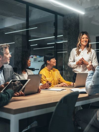 A woman leads a meeting with colleagues in a modern office.