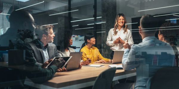 A woman leads a business meeting with engaged colleagues around the table.