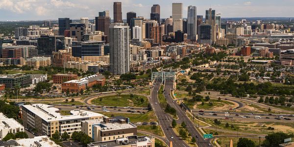 Aerial view of a city skyline with highways and green spaces.