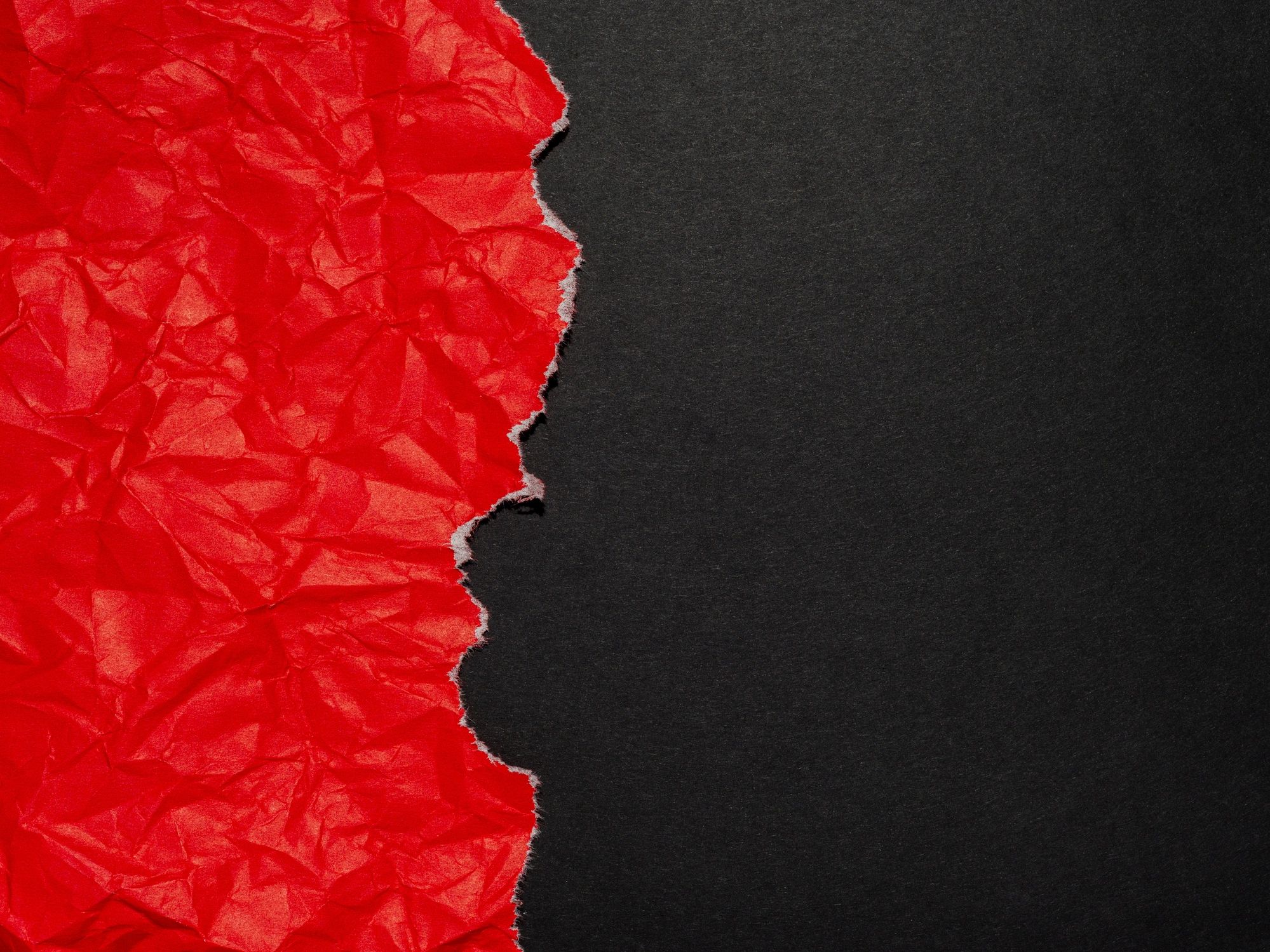 Torn red paper on black background.