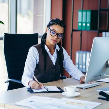 Professional woman taking notes at her desk in a modern office.