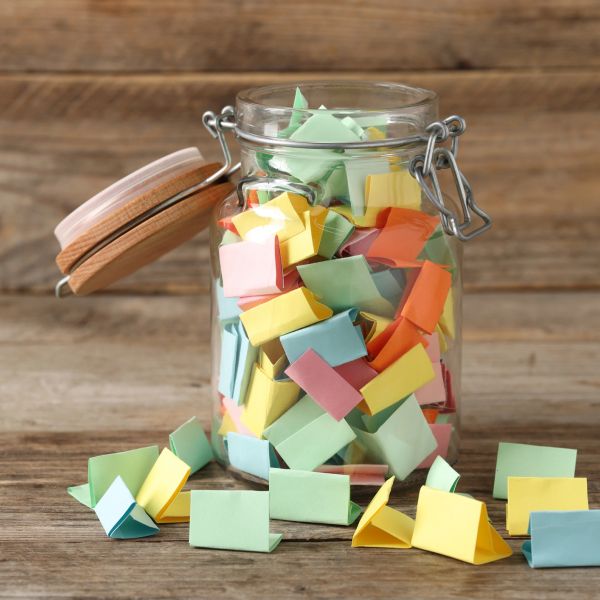 Glass jar filled with colorful folded notes.