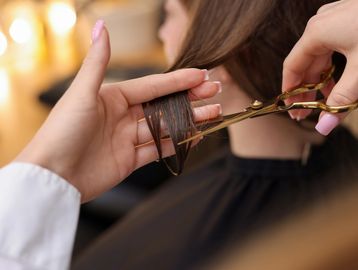 Haircut in progress with scissors trimming wet hair.