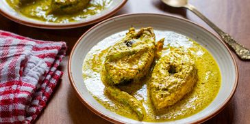 Plate of fish curry with a creamy yellow sauce on a wooden table.