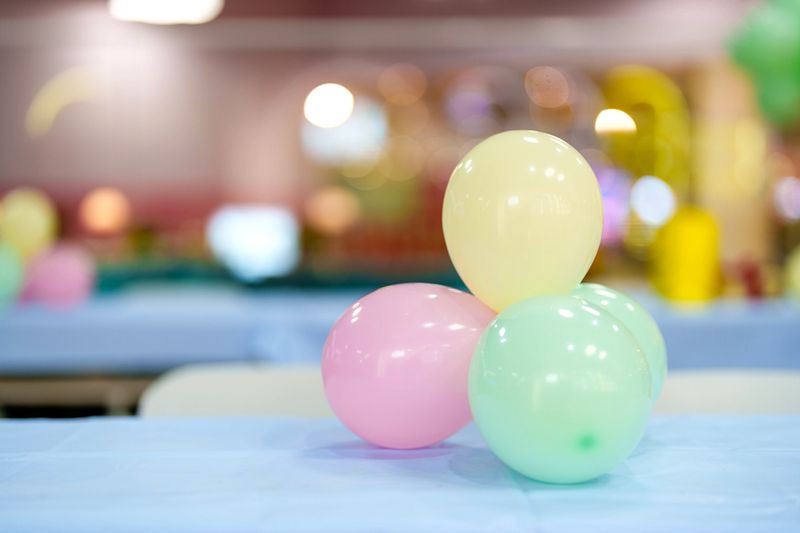 Close-up of pastel colored balloons decoration placed on a table with blurred festive background, suitable for celebration and event concepts.