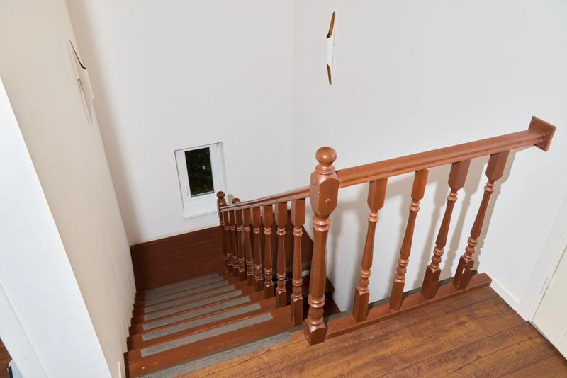A beautifully crafted wooden staircase elegantly ascends to a welcoming upper level, enhanced by crisp white walls