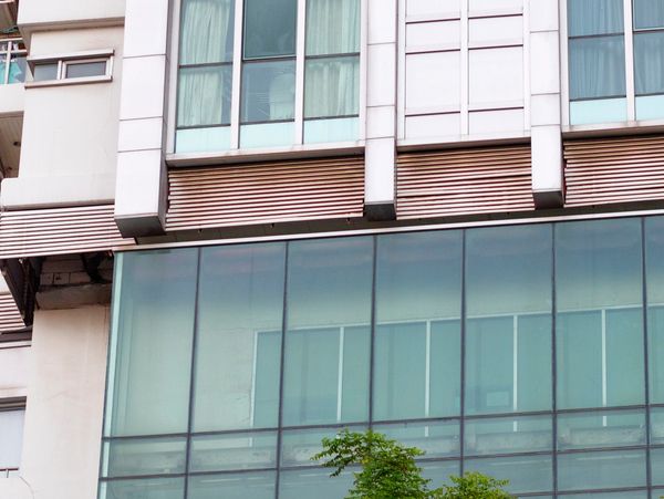 Modern building facade with large glass windows and greenery below.