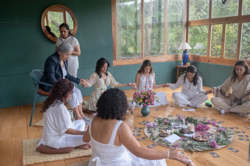 women sitting in a circle around a flower altar performing a spiritual ceremony or ritual
