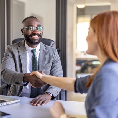 Businessman smiling and shaking hands with a woman in an office.