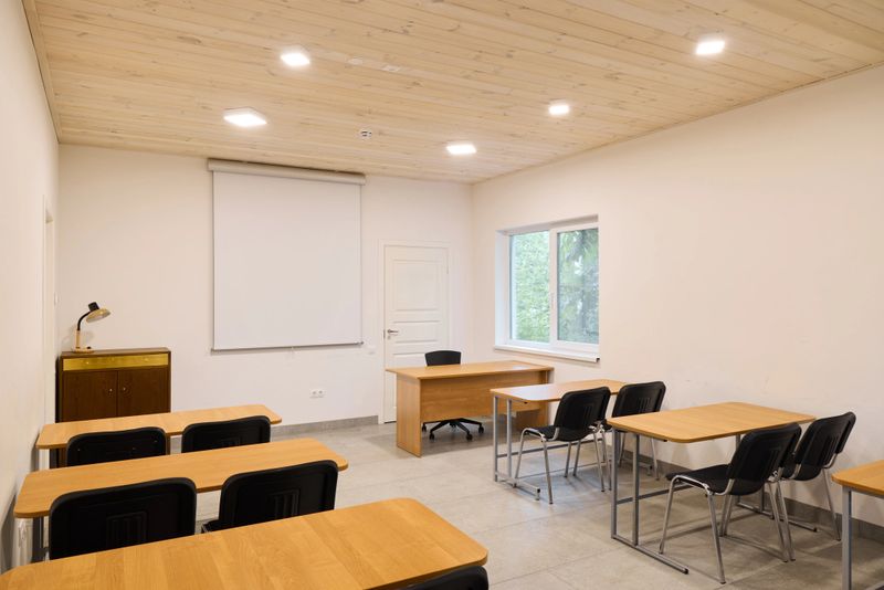 A bright and spacious classroom that includes desks, a projector, and benefits from plenty of natural light