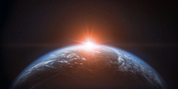 Sunrise from space over Earth with stars in the background.