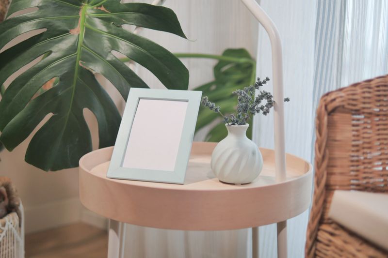 A well-decorated table holds a vase with flowers and an empty frame.