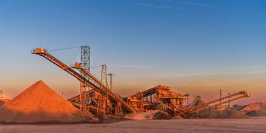Industrial conveyor system moving gravel at sunset.
