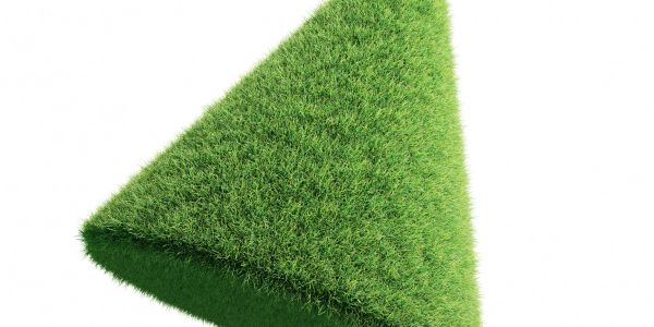 A triangular prism covered in lush green grass against a white background.