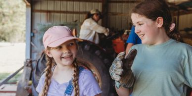 Two girls sharing a moment in a farm setting.
