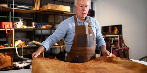 Man examining a large piece of leather in a workshop.