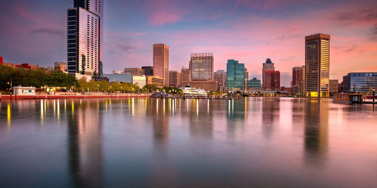 Baltimore skyline at sunset reflecting on the harbor water.