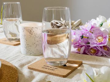 Two glasses of water with flowers on a table.
