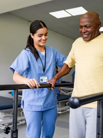 Healthcare worker assisting elderly man with walking exercises.