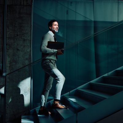 Man walking up stairs holding a laptop.