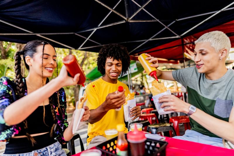 Young friends eating pastel at a street market