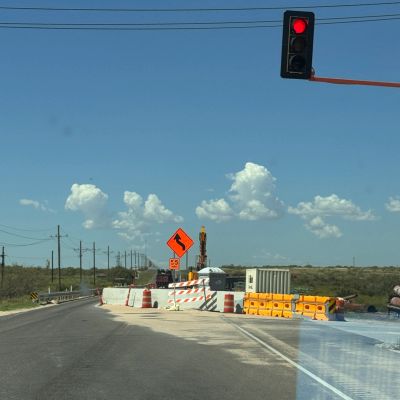 Red traffic light at road construction site with caution signs.