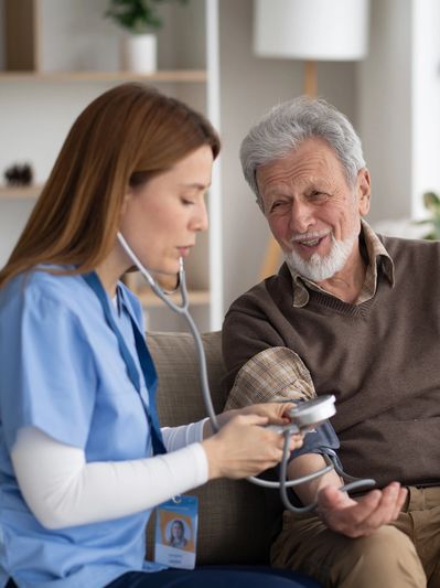 Nurse checking elderly man's blood pressure at home.