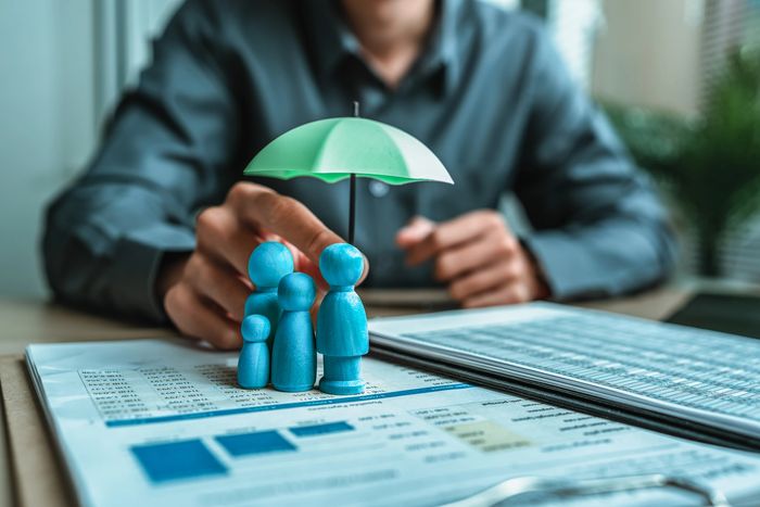 Person holding umbrella over family figurines
